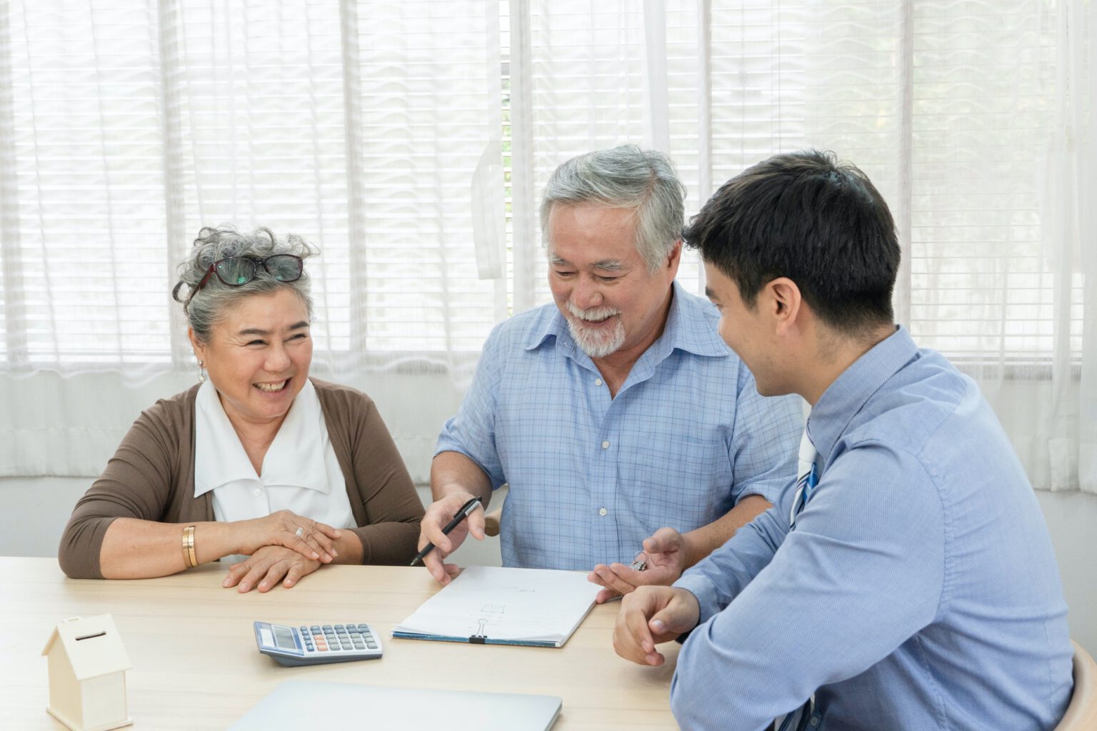 Asian senior man signing on agreement contract with agent for buying house